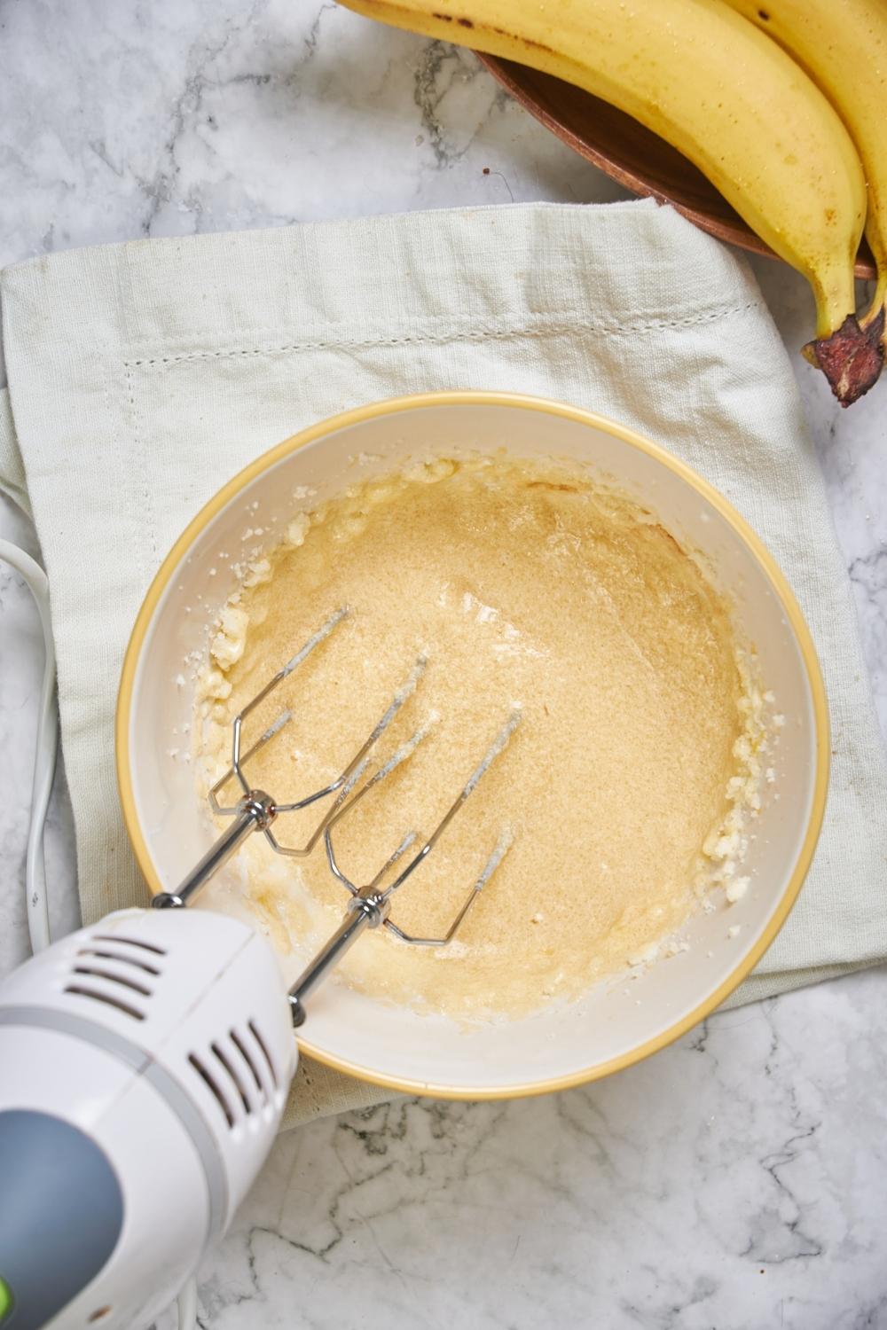 An electric mixer mixing cake batter in a bowl.