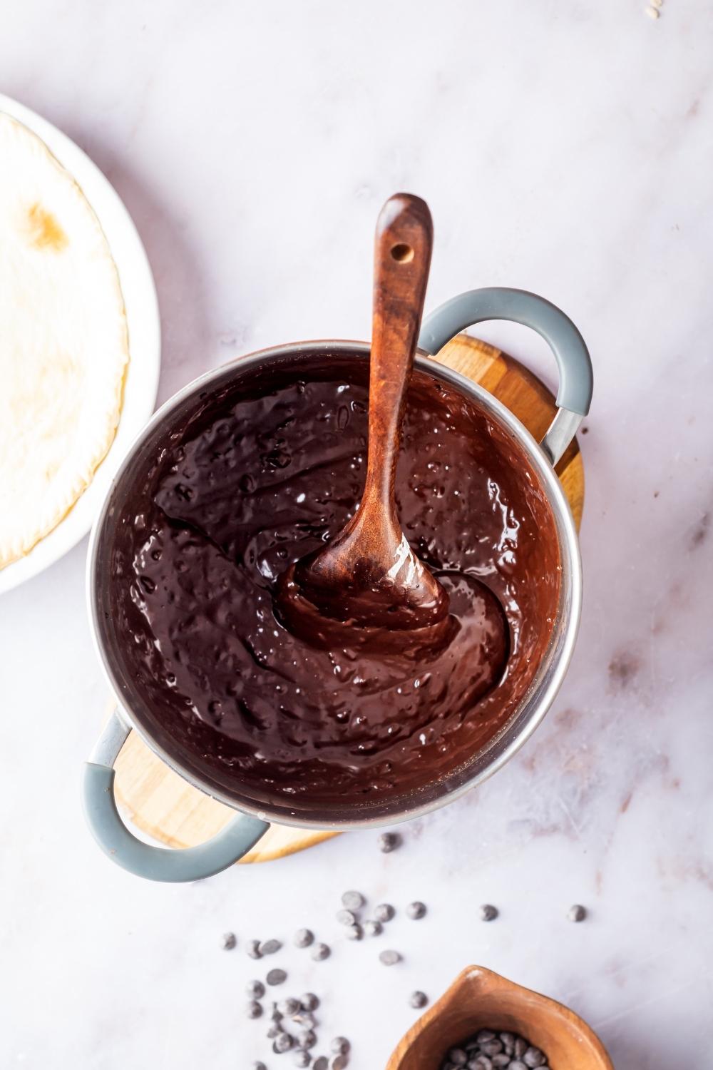 Chocolate pudding in a pot with a wooden spoon.