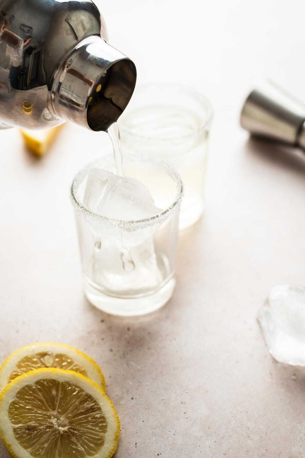 lemon drop alcohol being poured into sugar rimmed shot glasses