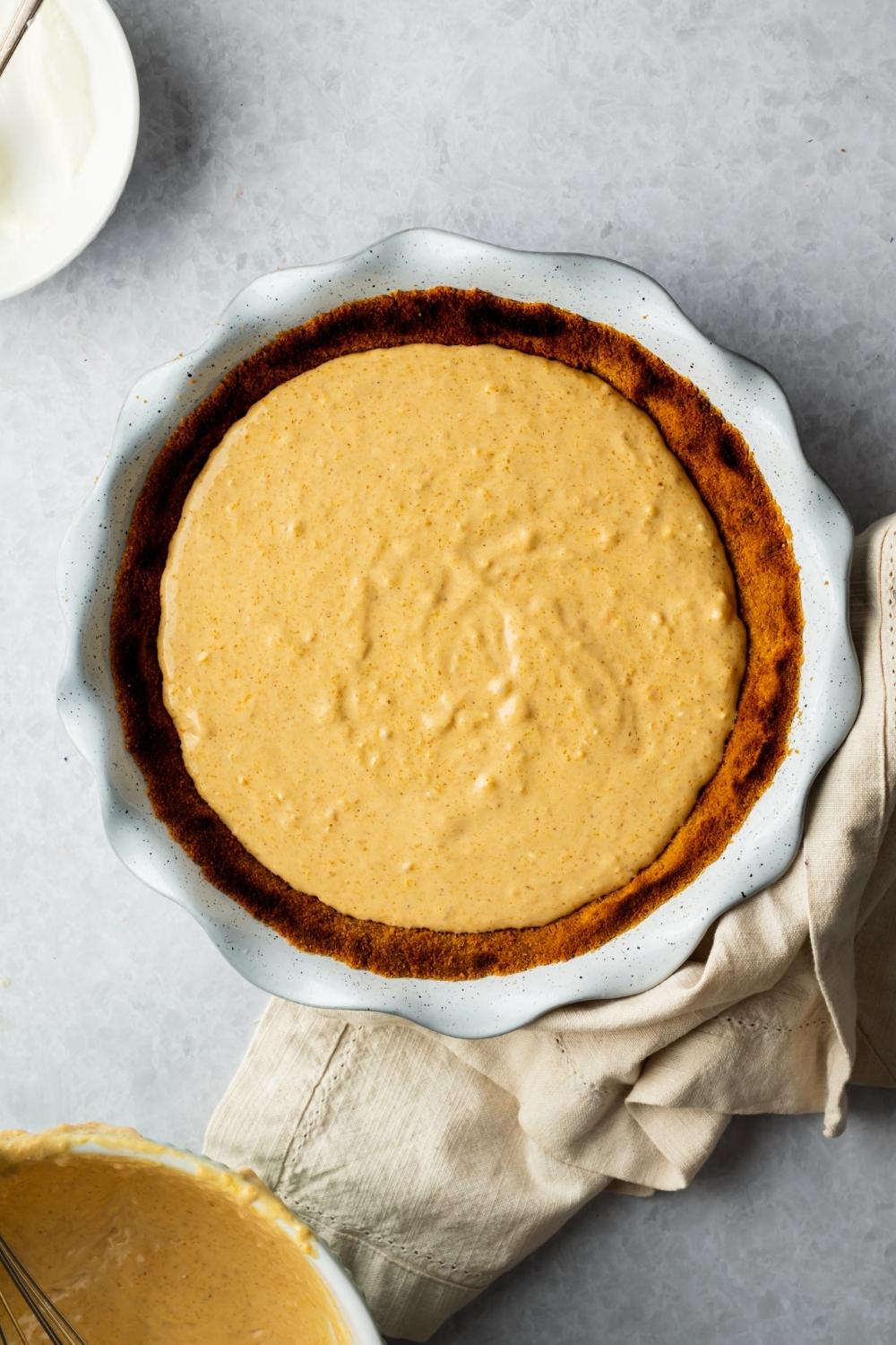 Pumpkin pie filling on top of a crust that is in a pie dish.