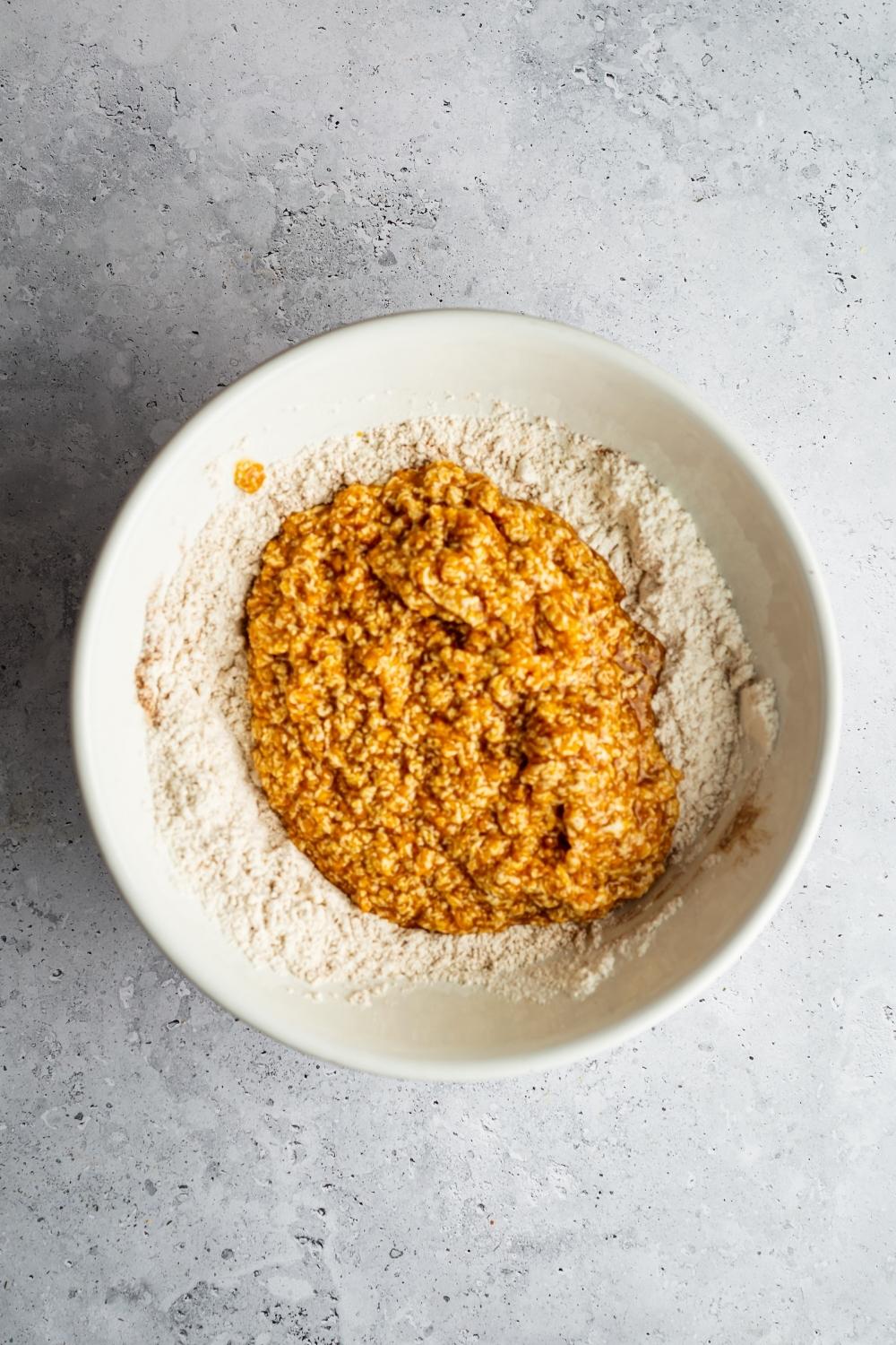 Sweet potato pound cake batter on top of flour in a white bowl.