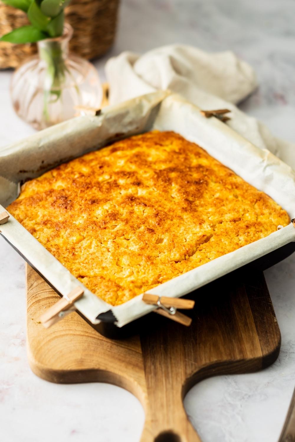 Sweet corn cake in a baking dish lined with parchment paper.