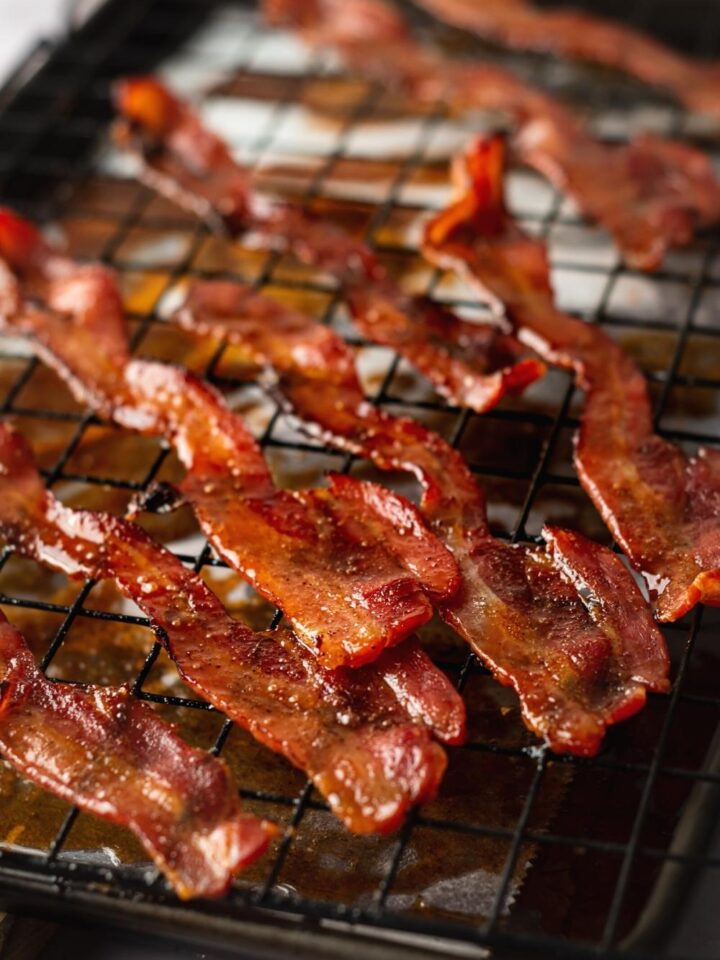A bunch of slices of million Dollar bacon on a wire rack on top of a baking sheet mine with parchment paper.