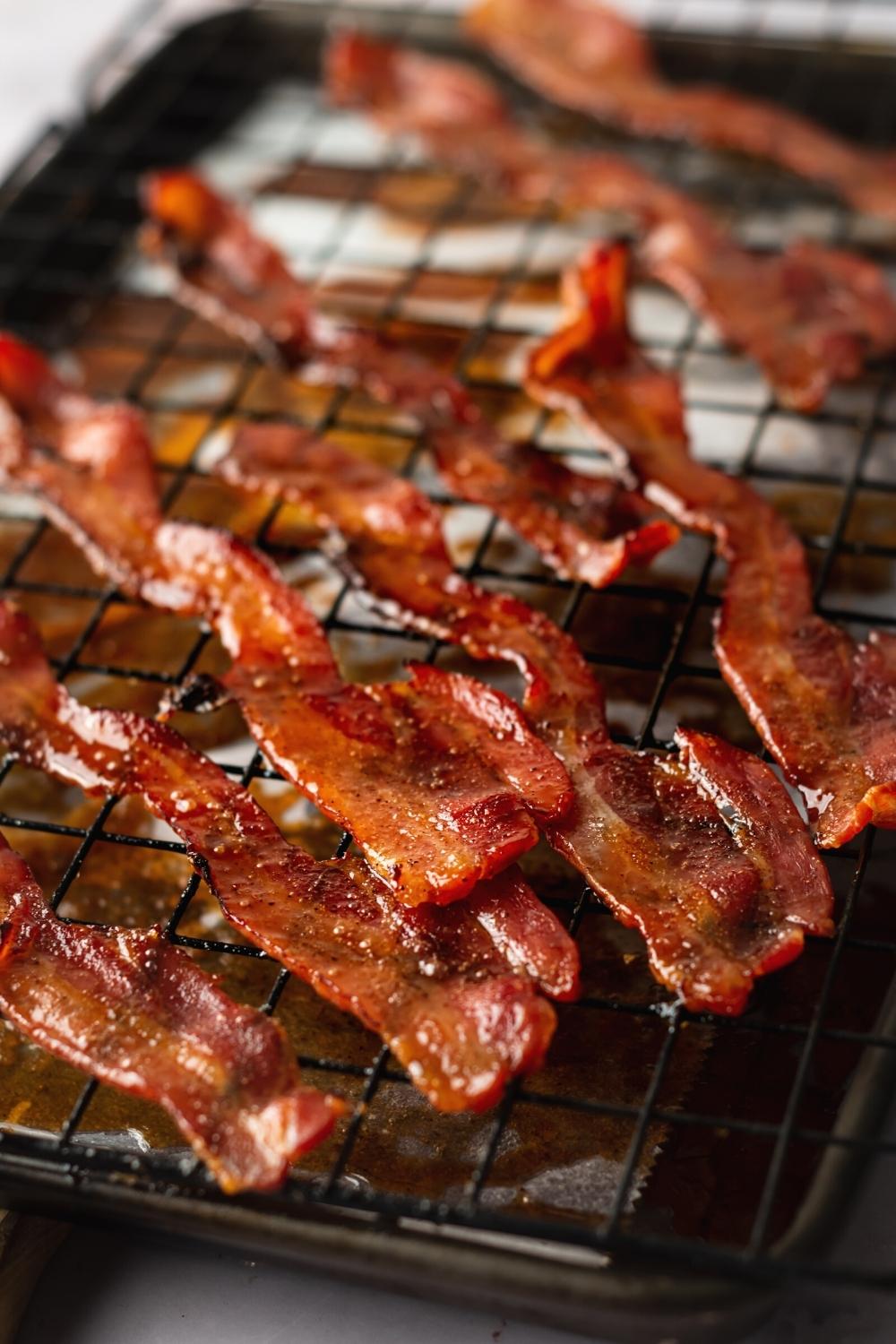 A bunch of slices of million Dollar bacon on a wire rack on top of a baking sheet mine with parchment paper.