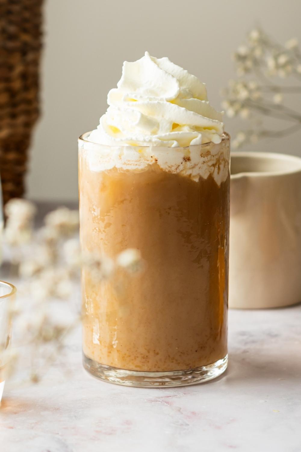 A glass of pumpkin cream cold brew with whipped cream on top.