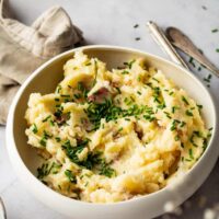 A white bowl that is filled with Redskin mashed potatoes.