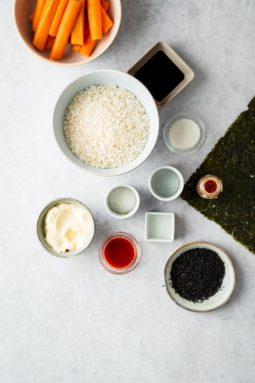 individual bowls of rice, carrots, black sesame seeds, mayonnaise, and other sushi bake ingredients