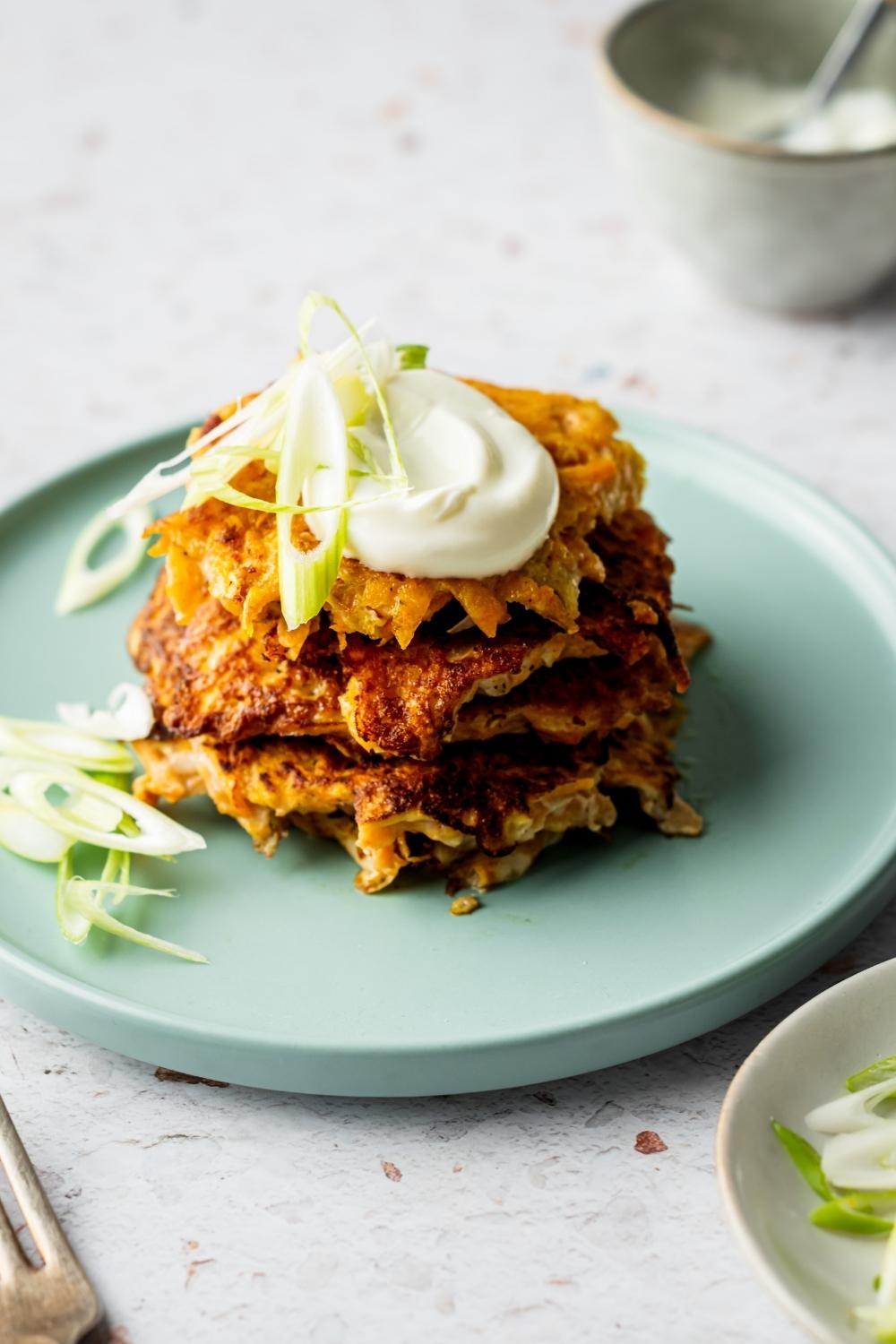Four sweet potato hash browns with a dollop of sour cream on top.
