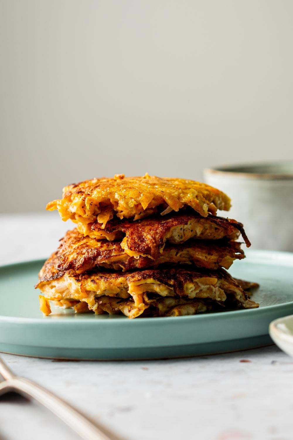 A stack of four sweet potato hash browns on a plate.