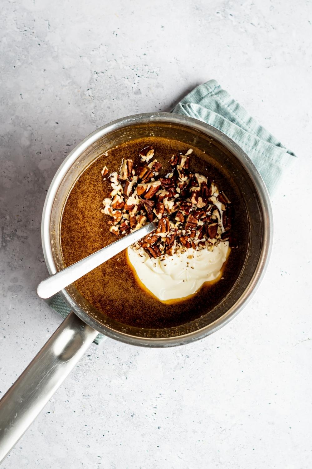 Heavy cream, chopped pecans, and melted brown sugar in a part with a spoon in it.