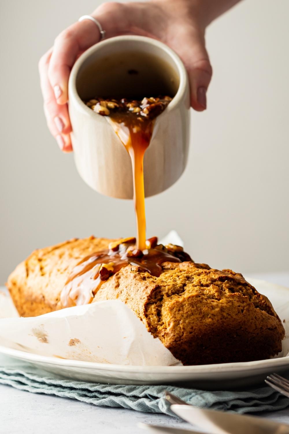 Hand pouring a maple brown sugar glaze on top of a sweet potato poundcake.