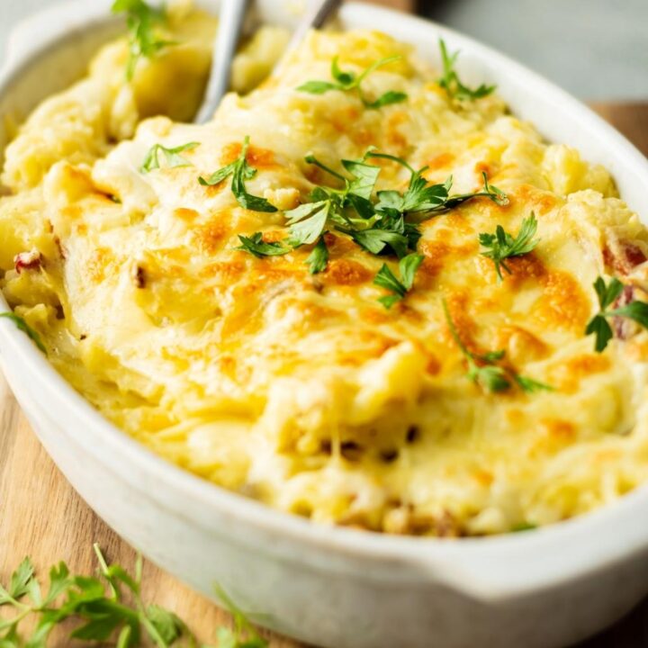 A white casserole dish with twice baked mashed potatoes in it.