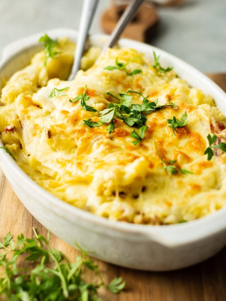 A white casserole dish with twice baked mashed potatoes in it.