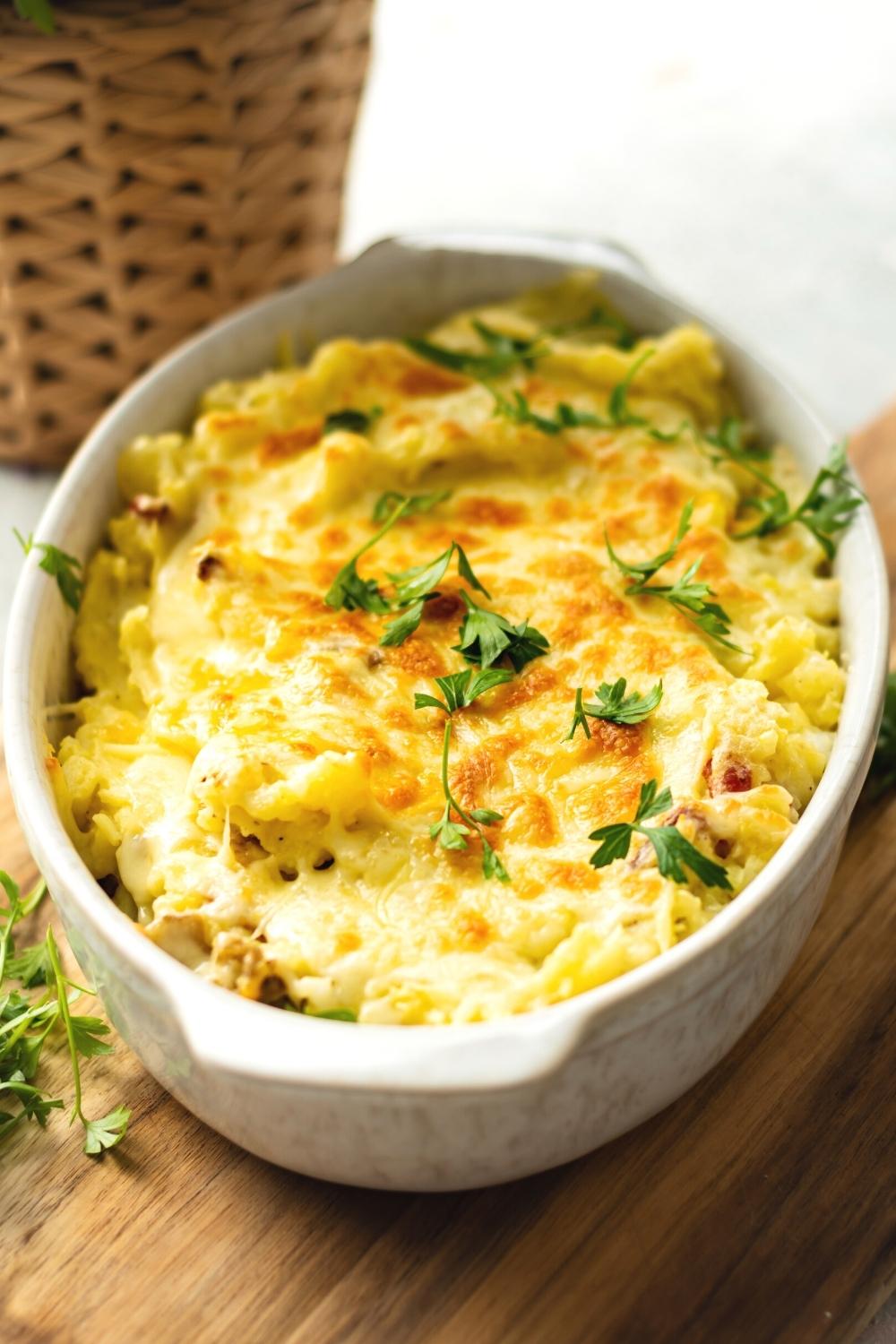 Twice baked mashed potatoes in a white casserole dish.