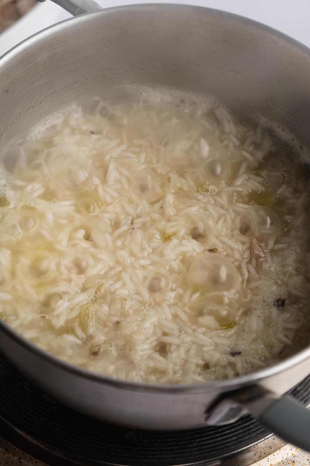 A large pot with rice cooking in chicken broth.