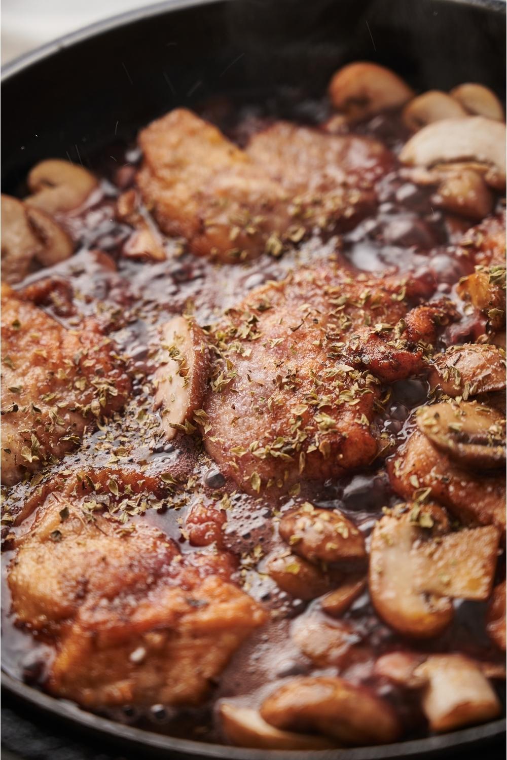 Close up of cooked chicken marsala bubbling in a pan.