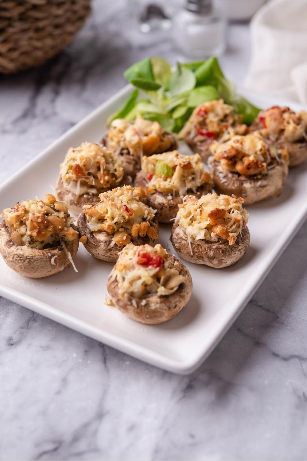 Red lobster crab stuffed mushrooms on a white plate with a garnish of greens.