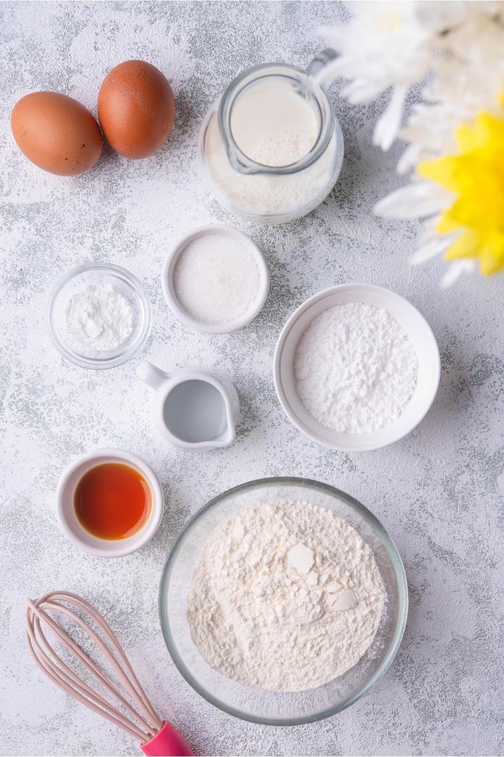 An assortment of ingredients for funnel cakes including flour, eggs, vanilla extract, and powdered sugar.