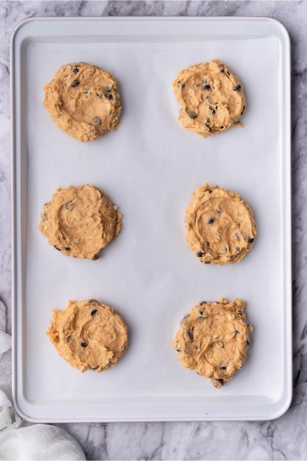 Unbaked sweet potato cookies portioned on a baking sheet lined with parchment paper.