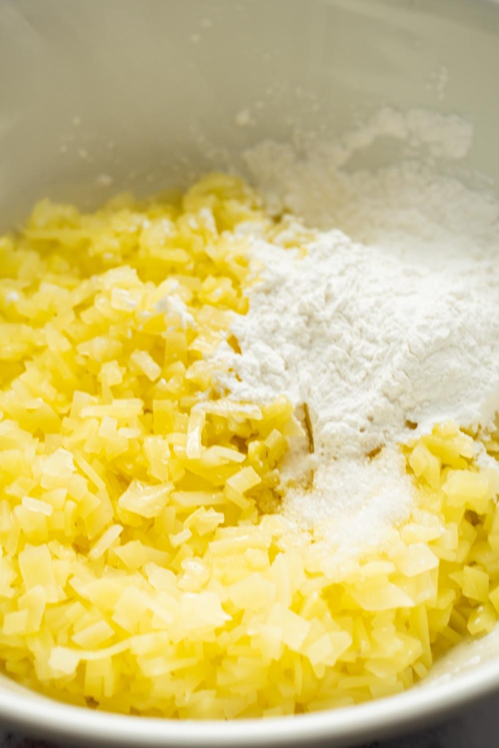 A bowl with finely diced potatoes. Cornstarch and salt has just been added to it.