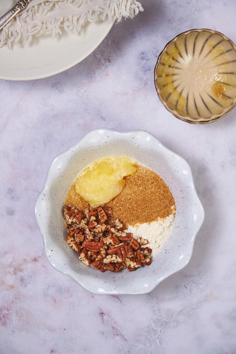 White bowl with ingredients for pecan brown sugar crumble topping.
