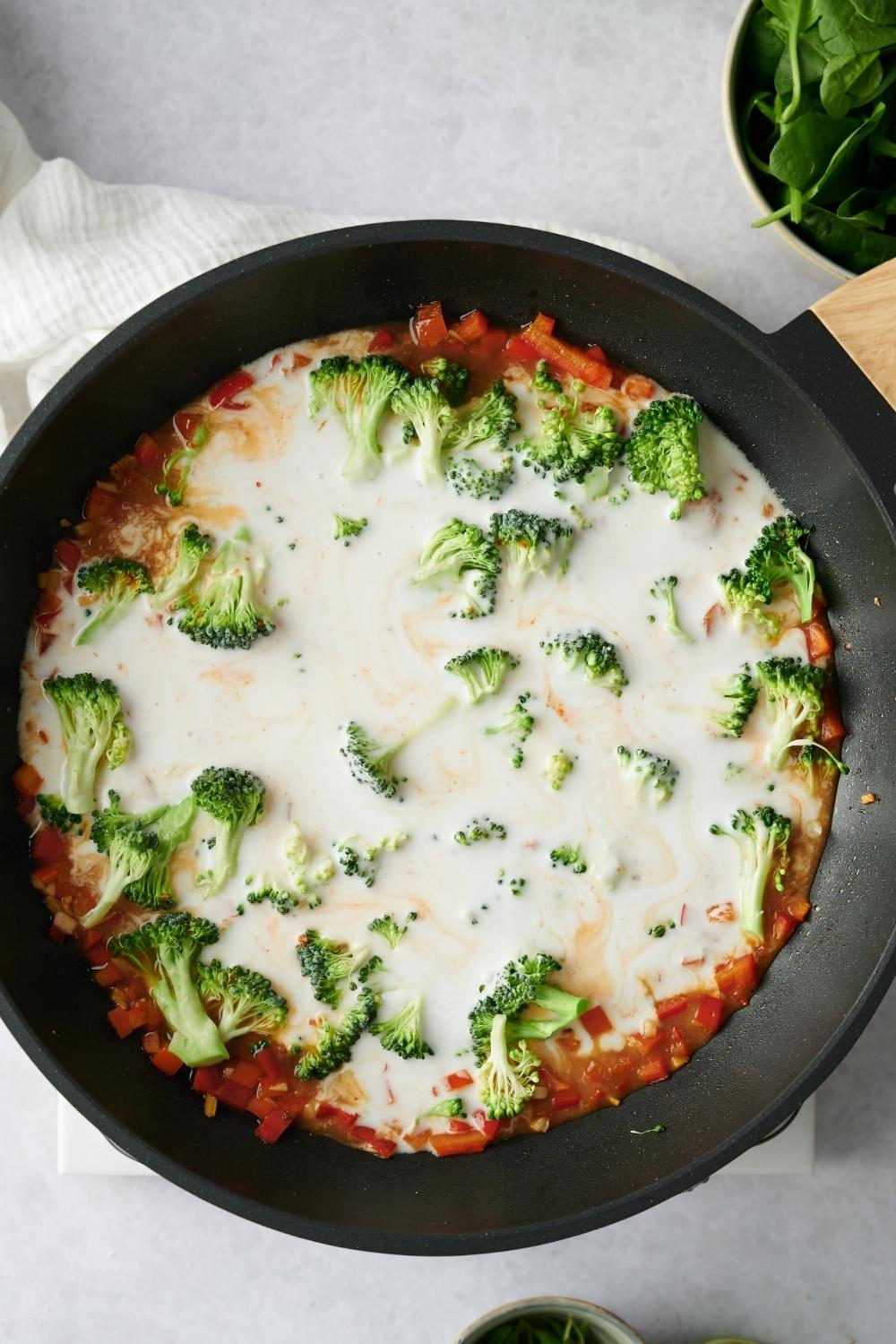 A hot pan with cooked veggies. Coconut milk has just been added.