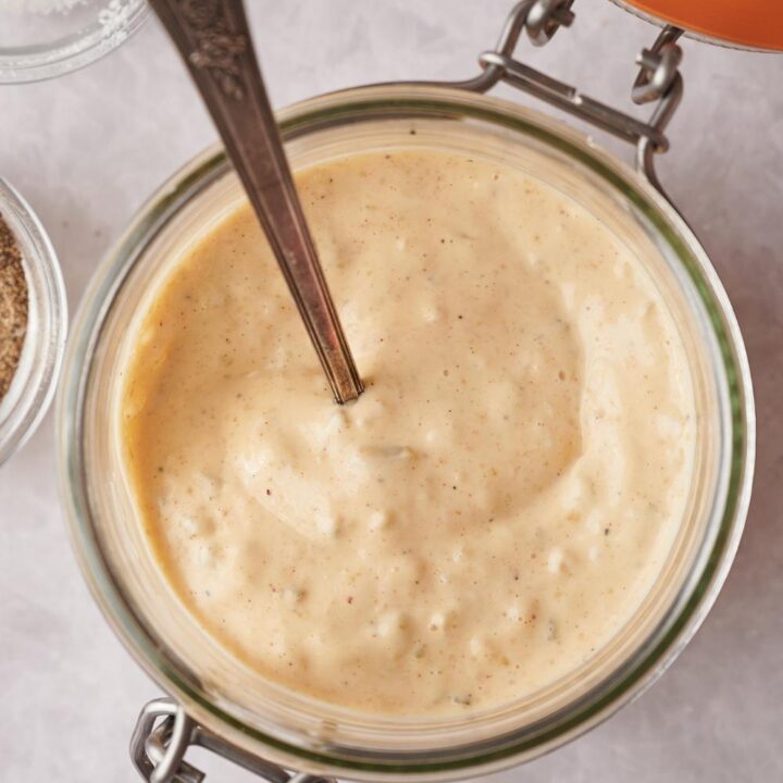 A mason jar containing homemade big Mac sauce with a spoon in it.