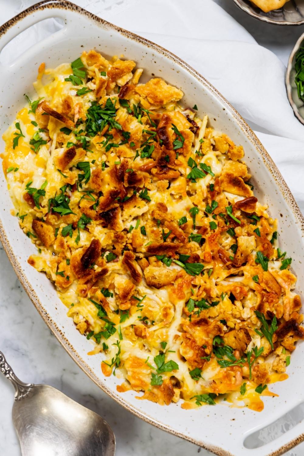 A casserole dish with baked Crack Chicken garnished with parsley in it.