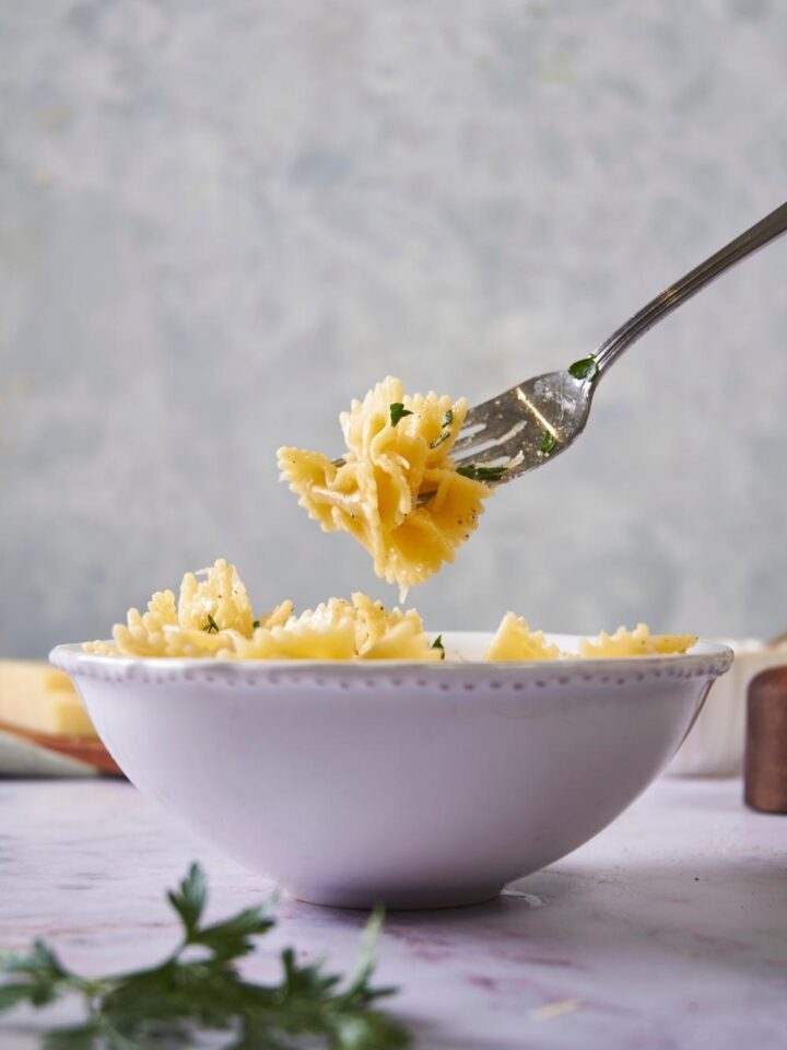 Microwaved pasta in a white bowl with a fork grabbing a bite of pasta.