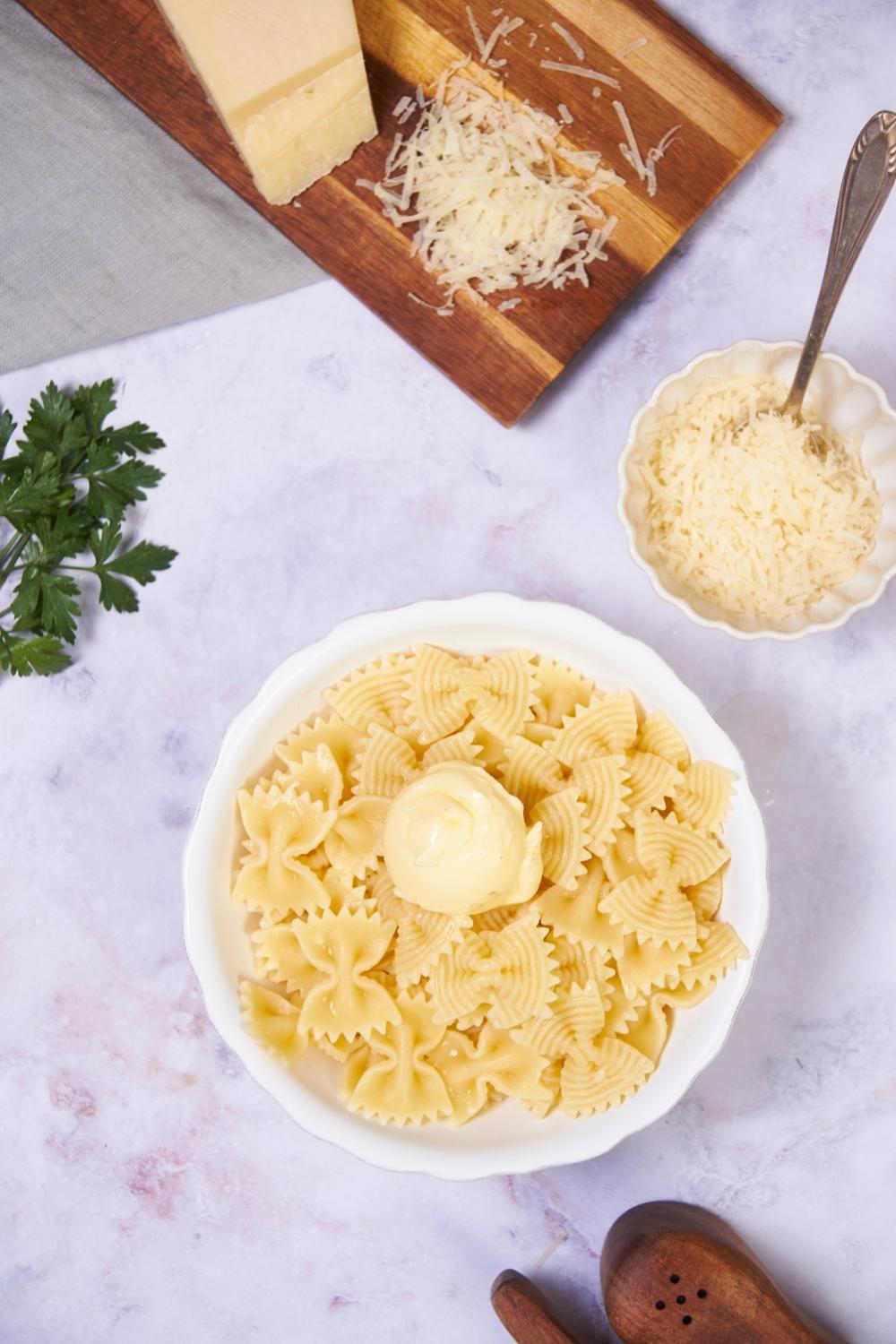 A bowl of microwaved pasta next to a small bowl of parmesan cheese.