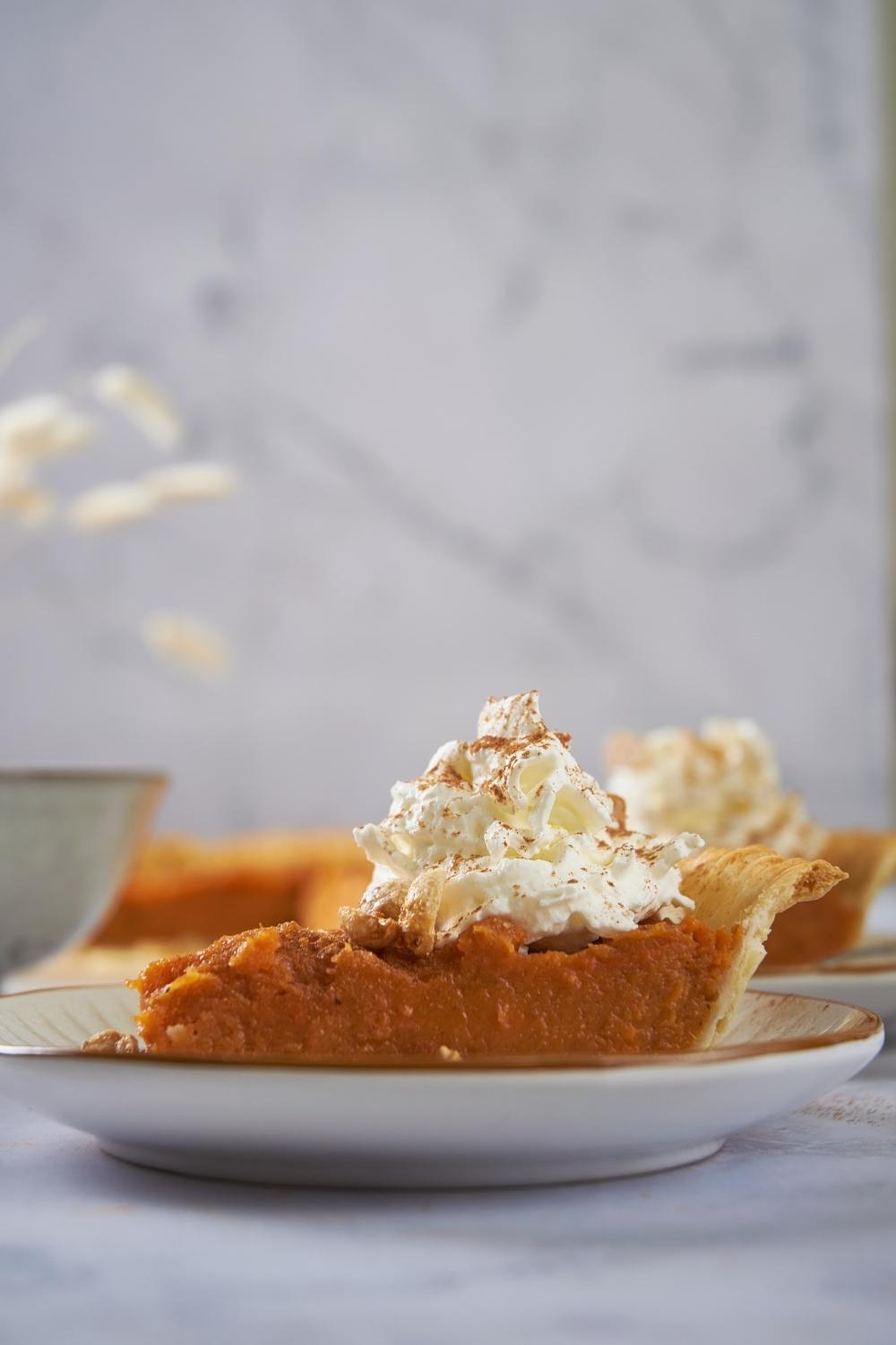 Patti Labelle's sweet potato pie on a white plate topped with whipped cream.