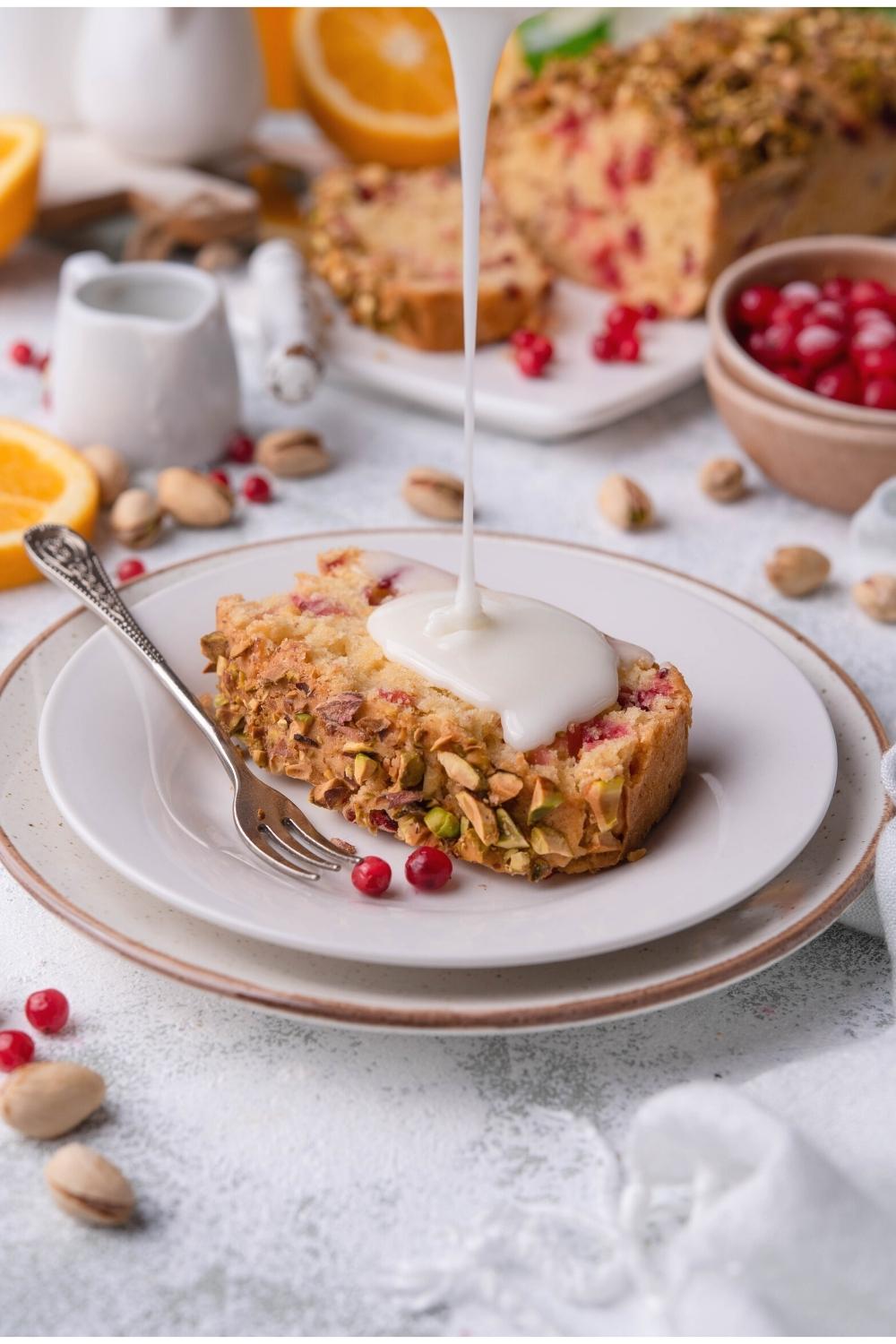 A slice of cranberry bread with a glaze being drizzle on top.