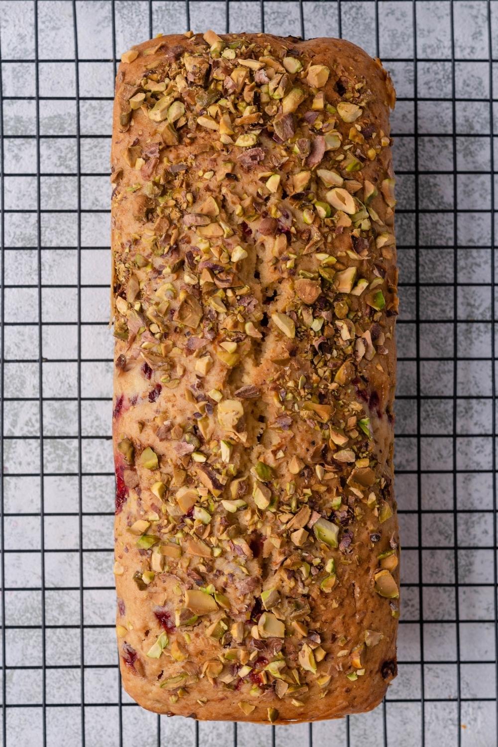 A loaf of cranberry nut bread cooling on a wire rack.