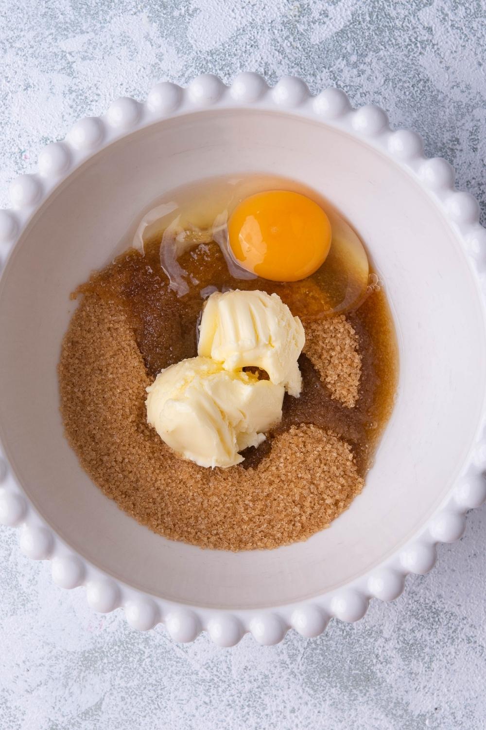 A mixing bowl with brown sugar, butter, and egg.