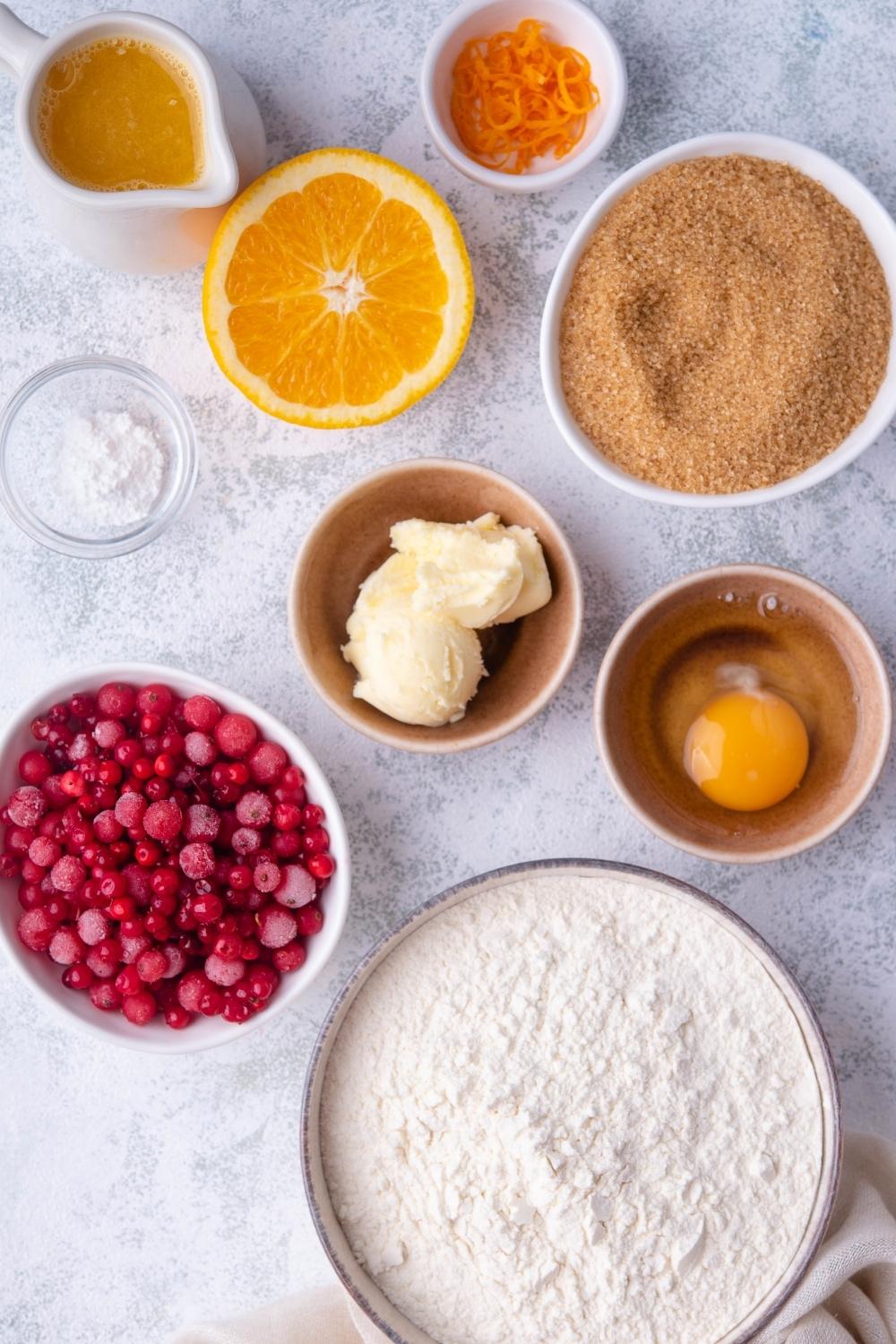 A countertop with eight bowls containing the ingredients to make cranberry nut bread.