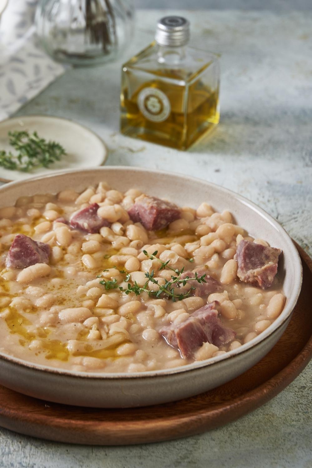 A big bowl of great northern beans with ham served on a wooden plate tray.