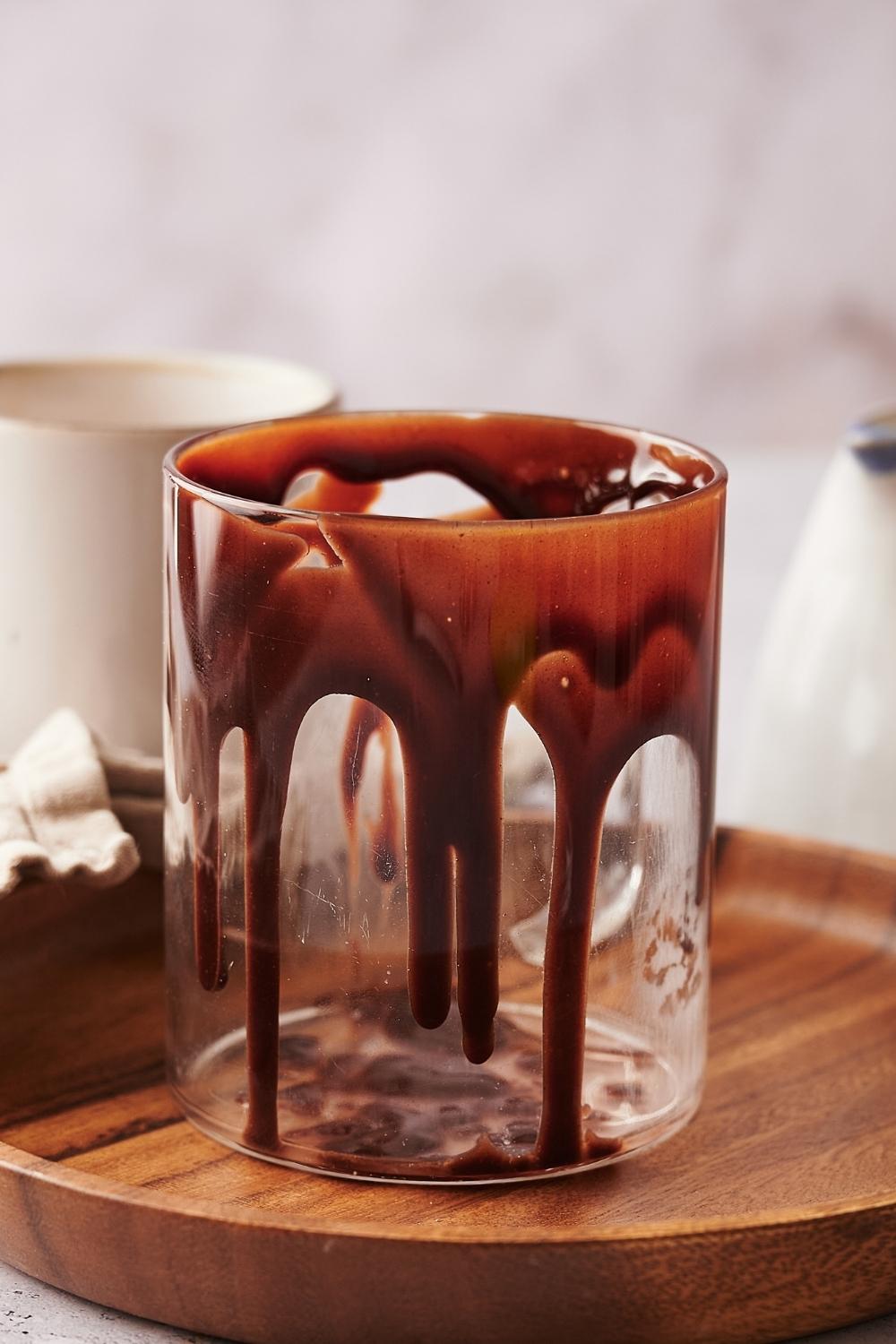 A clear glass mug with chocolate syrup drizzled on the sides.