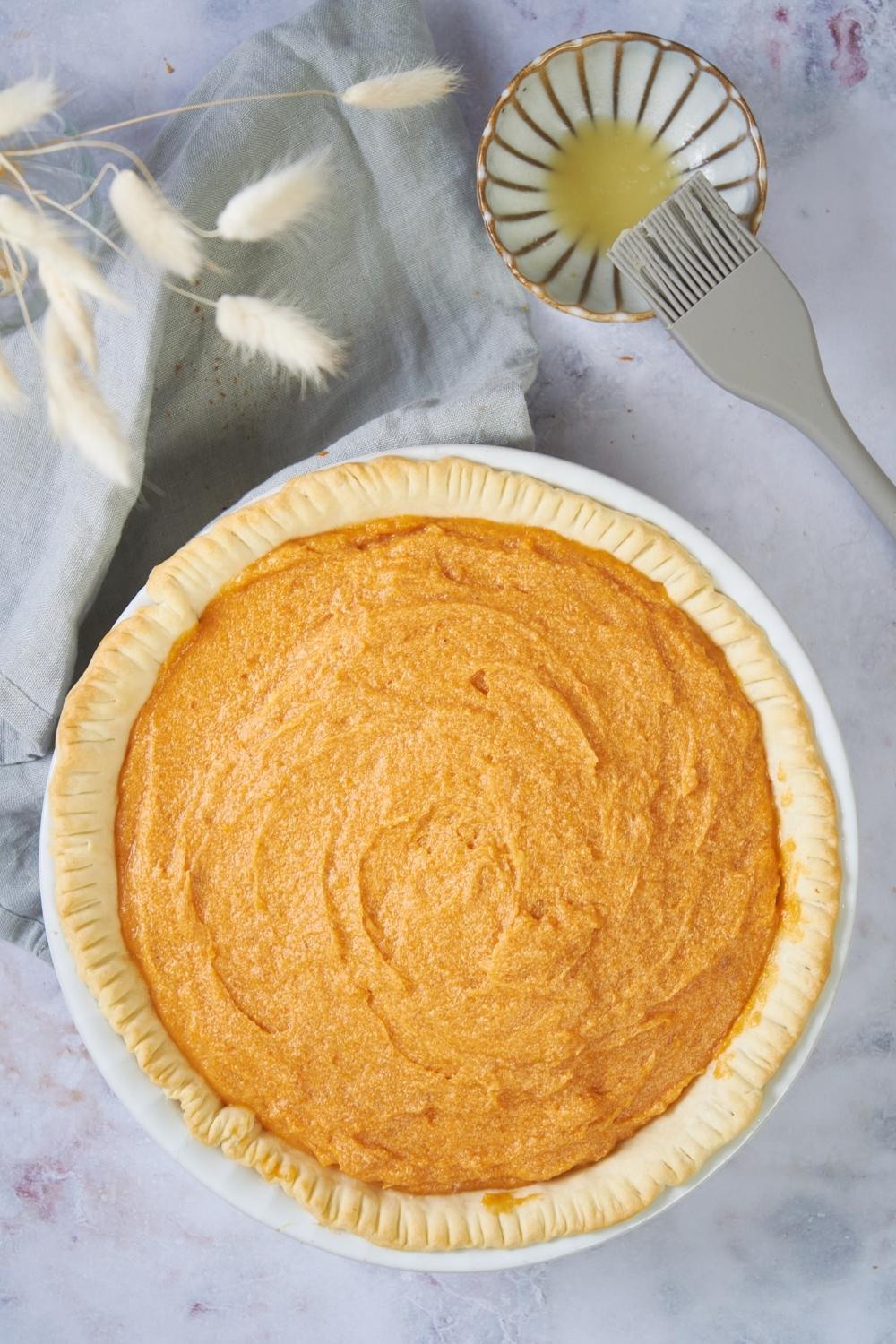 Patti Labelle's sweet potato pie unbaked next to a small bowl of melted butter.