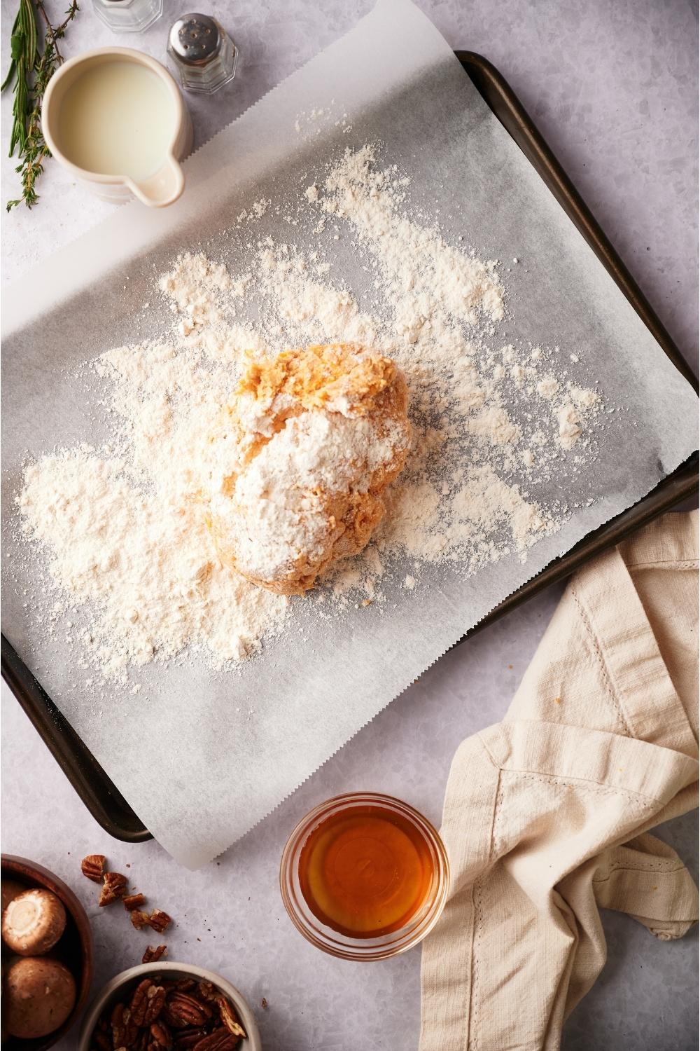 A baking sheet lined with parchment paper and biscuit dough covered in flour on the baking sheet.