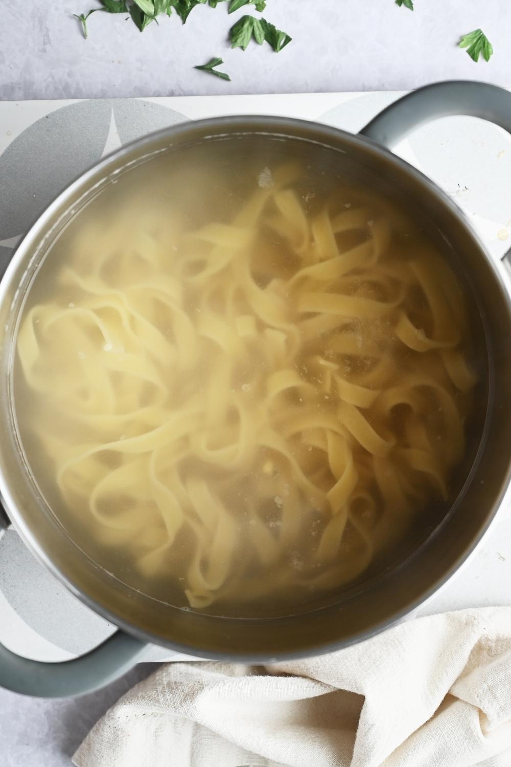 A pot with boiling water cooking fettuccini noodles.