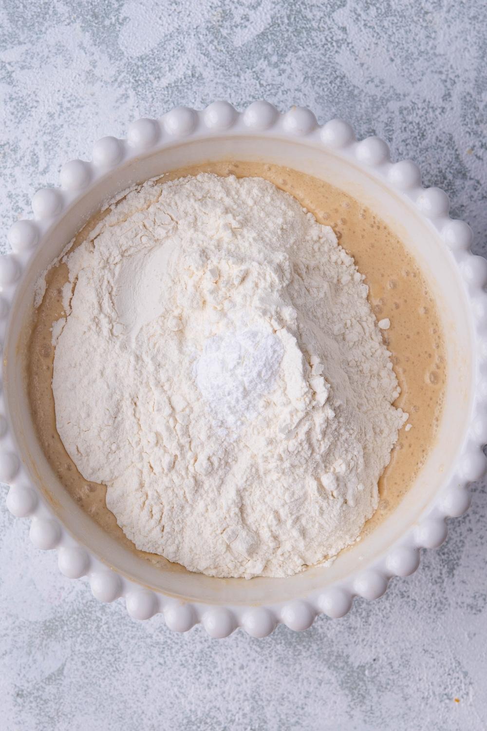 A bowl containing the combined wet ingredients, flour has just been added to it.