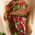 A southern meatloaf on a sheet of parchment paper in a baking dish.