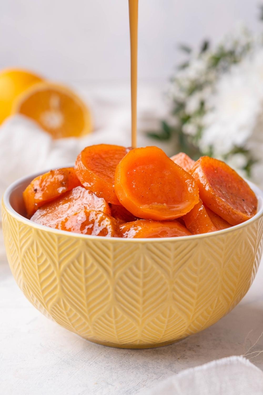 A bowl with candied yams in it. Extra sugar-syrup if being drizzled on top.