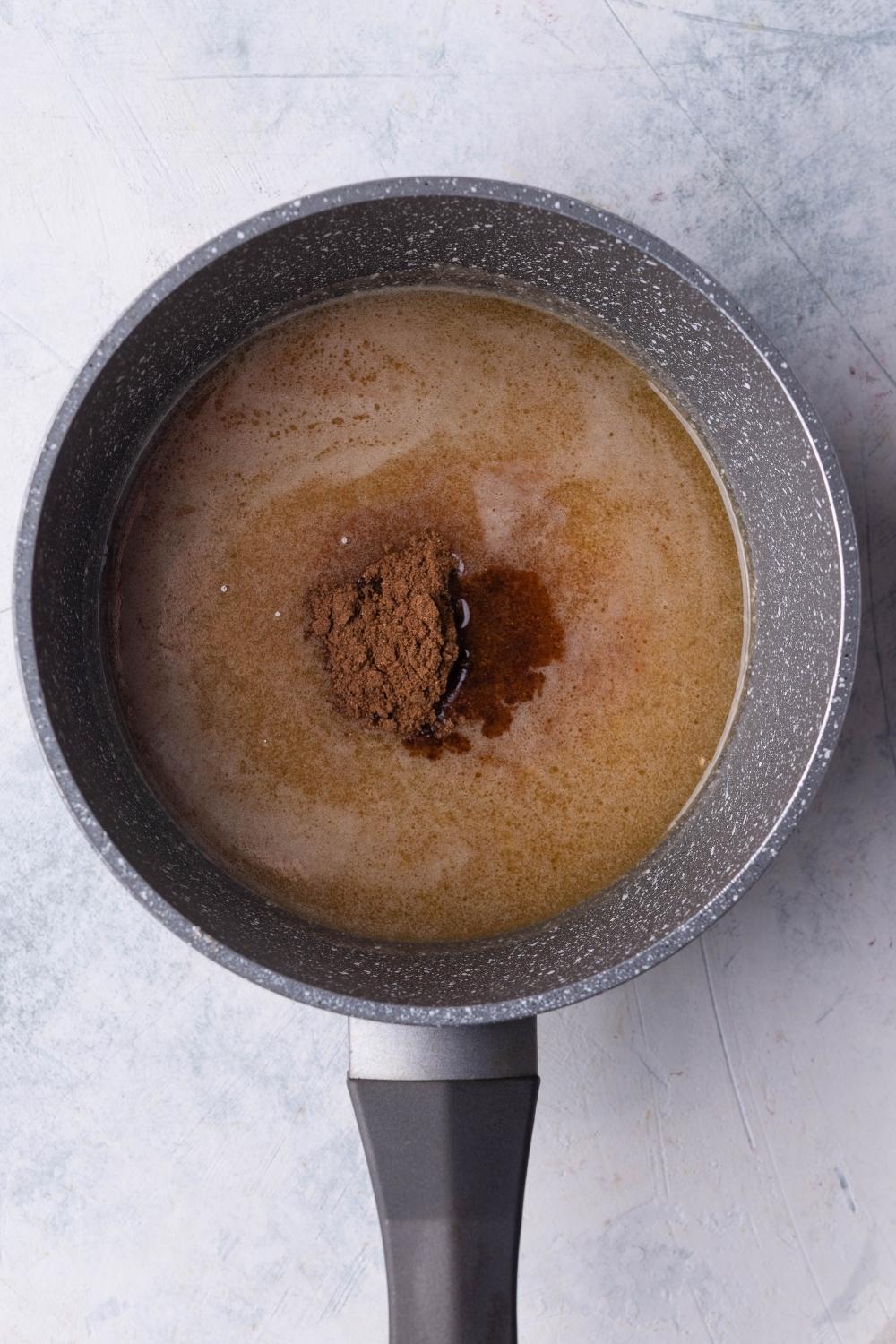 A sauce pot with brown sugar, melted butter, and granular sugar.