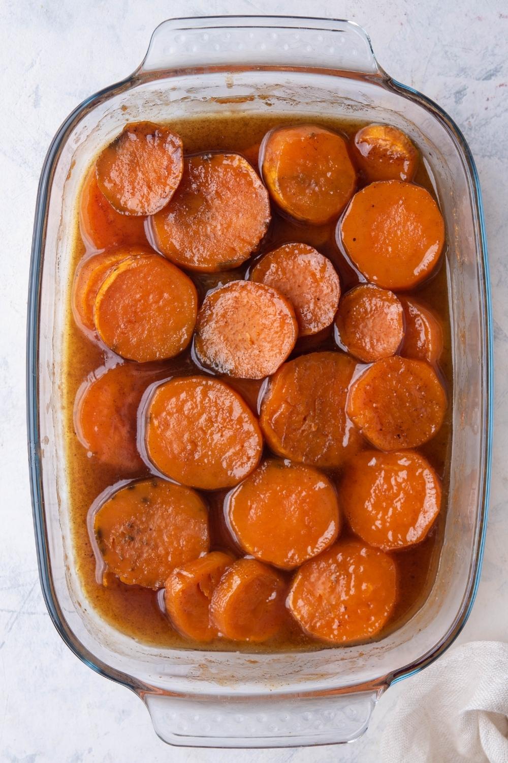 A baking dish with cooked sliced sweet potatoes and the brown sugar mix.