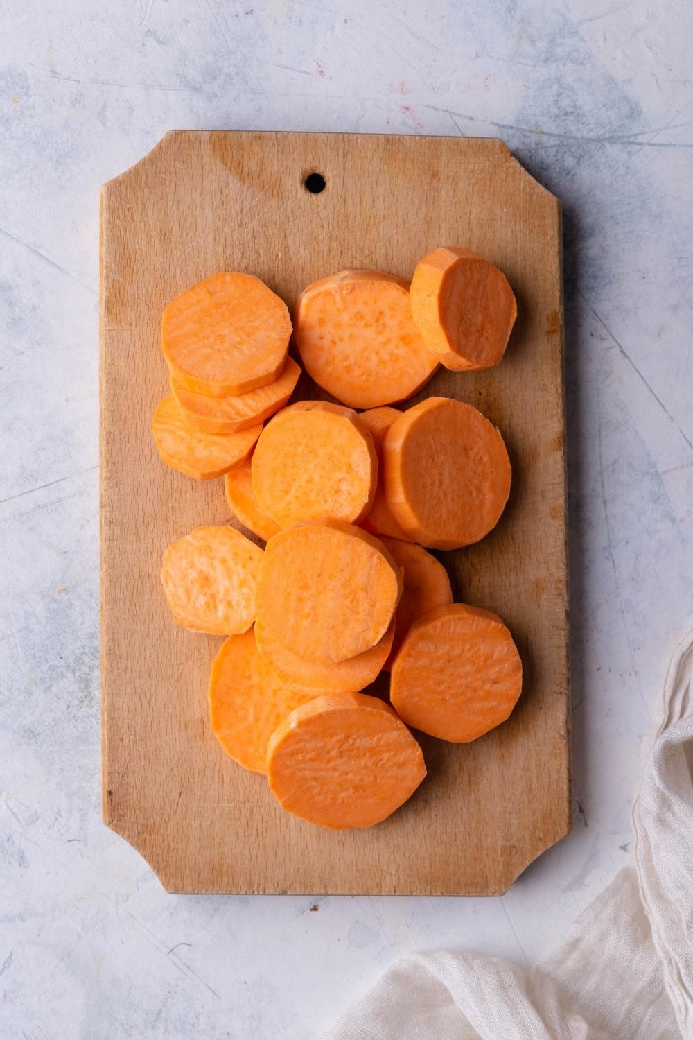 A cutting board with fresh sweet potato slices on it.