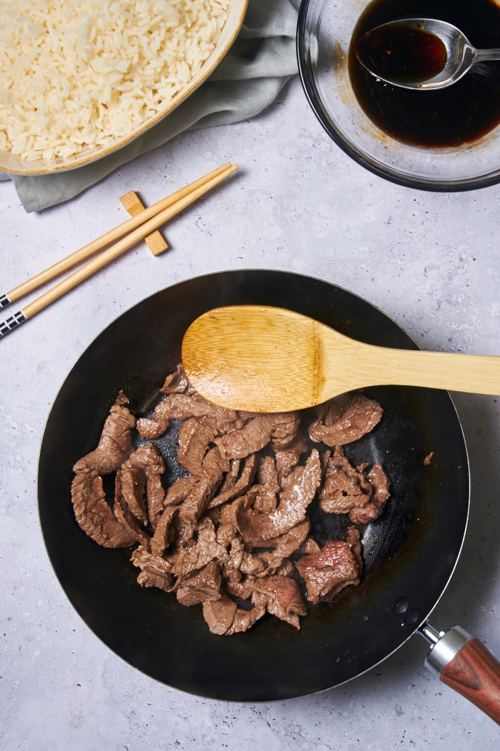 A black skillet filled with cooked beef and a wooden spoon in the skillet.
