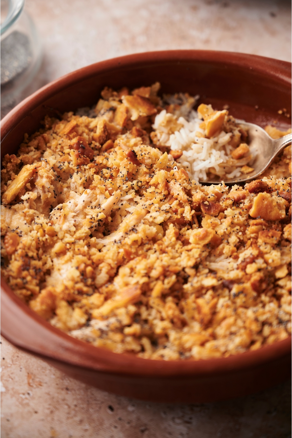 Poppy seed chicken casserole in a red casserole dish with a spoon in the dish.