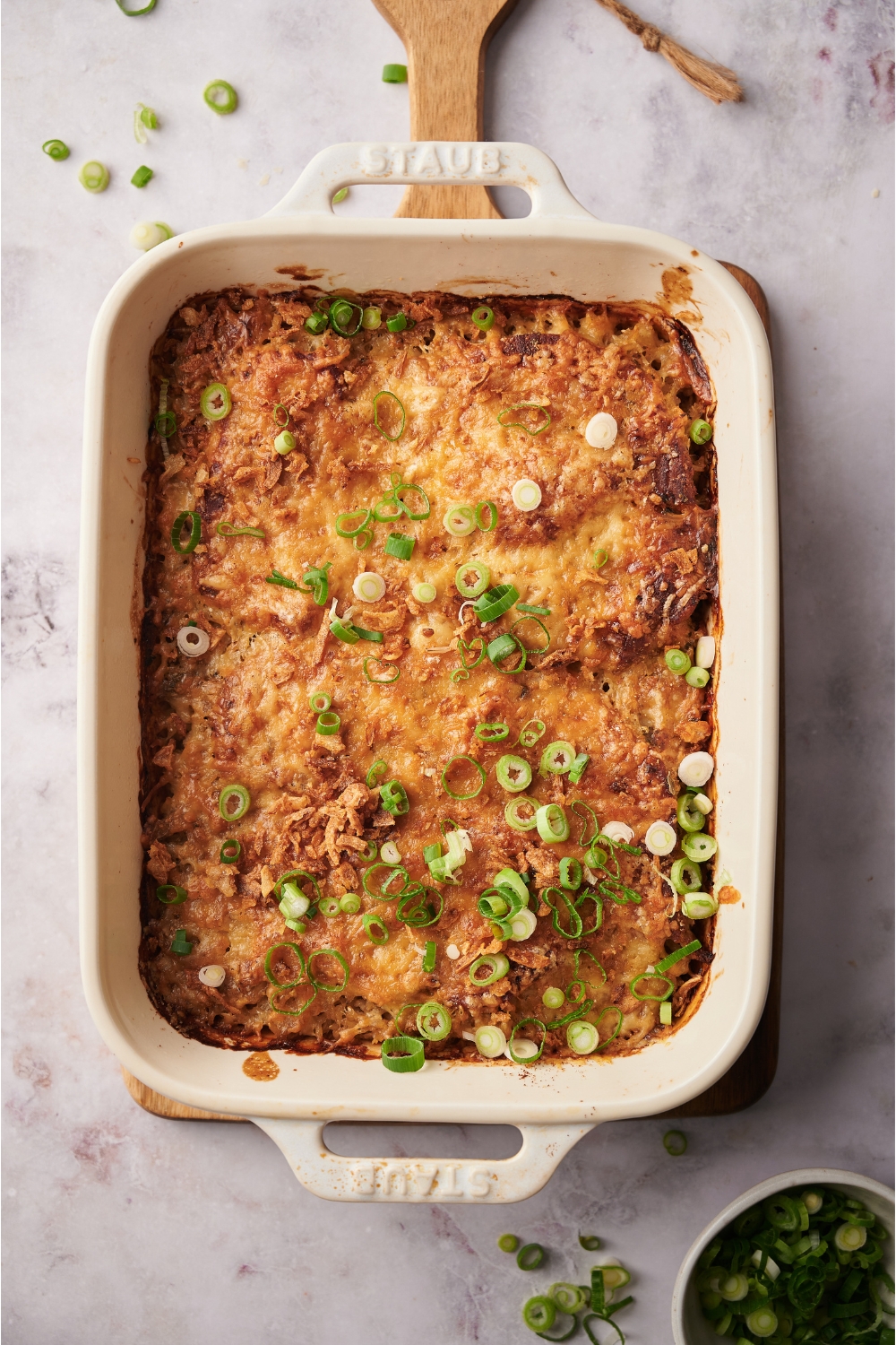 Green onions garnished on a freshly baked casserole in a white casserole dish.