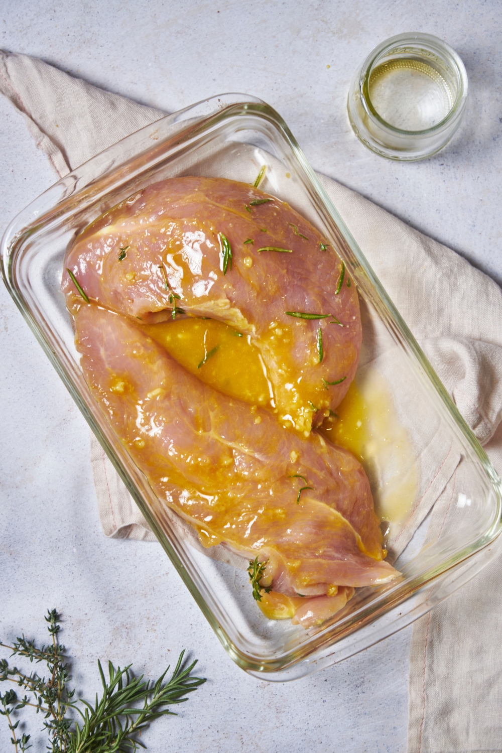 A clear baking dish filled with raw marinated turkey tenderloin.